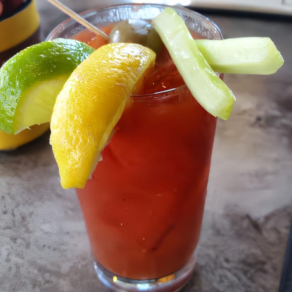 A Bloody Mary cocktail garnished with lemon, lime, cucumber spears, and olives.