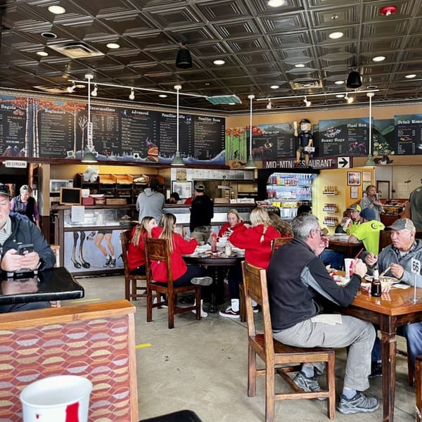 Customers dine inside Wasatch Bagel and Grill, with menu boards and a service counter in the background.