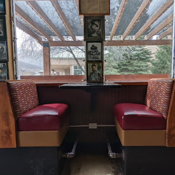 A cozy Wasatch Bagel and Grill booth with red seats, a small table, and framed pictures.