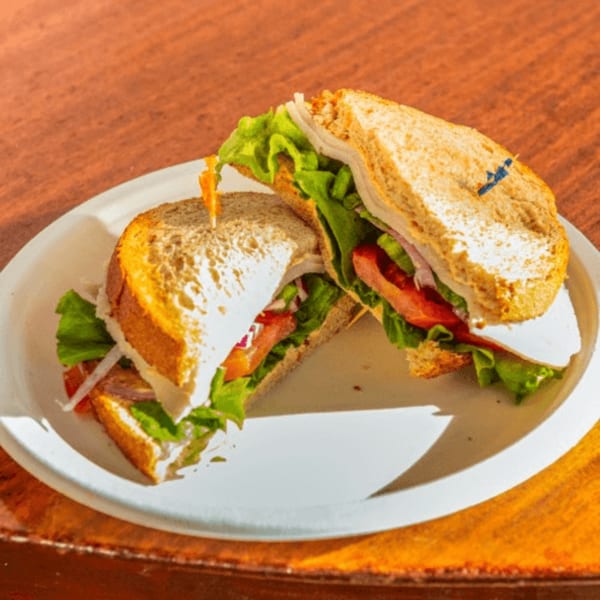 A turkey sandwich on whole wheat bread with lettuce, tomato, onion, and cheese, cut in half.