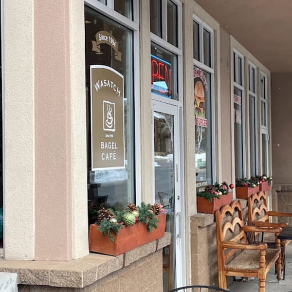 Exterior of Wasatch Bagel Cafe with a brown sign, window boxes, and outdoor seating.